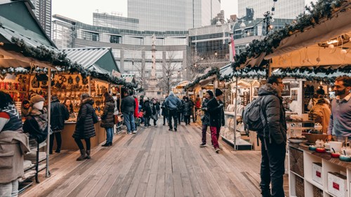Drukke kerstmarkt met verlichte kraampjes en bezoekers overdag