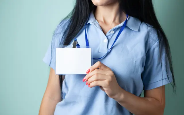 Vrouw in lichtblauwe polo houdt een leeg legitimatiebewijs aan een blauw keycord vast