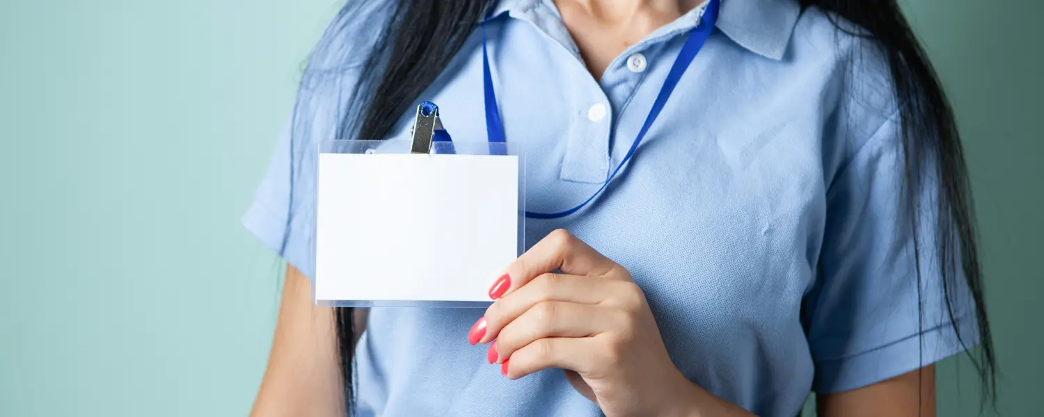 Vrouw in lichtblauwe polo houdt een leeg legitimatiebewijs aan een blauw keycord vast