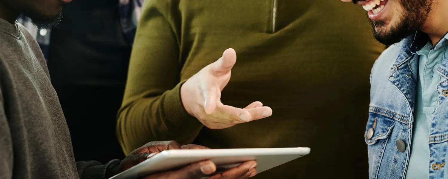 Drie ervaren collega’s kijken mee op de tablet van de nieuwe collega en leggen de werkzaamheden uit.