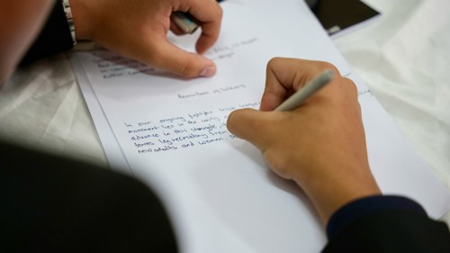 Kandidaat schrijft geconcentreerd een rapport uit.